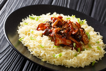 Spicy fried fresh shiitake mushrooms with sesame seeds served with rice closeup on a plate. horizontal