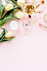 Female home office desk. Workspace with yellow tulip flowers, women's golden accessories, stationery on pink background.  Flat lay, top view.