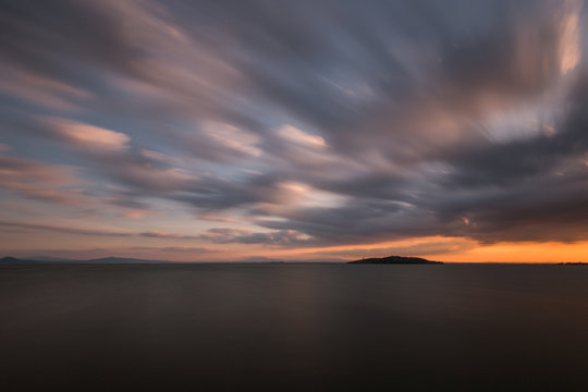 Beautiful wide angle, long exposure view of a lake at sunset, with an huge sky with moving clouds © Massimo