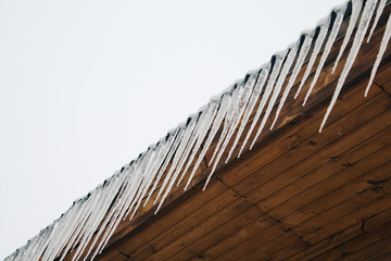 frozen icicles on the roof of the wooden house, top floor wooden mansion. Icy weather winter scene