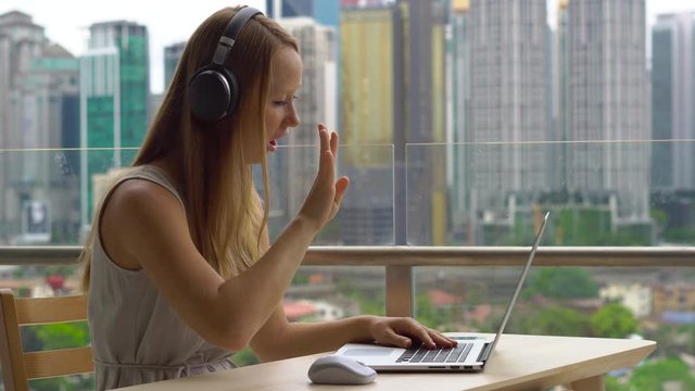 Remote techer has a conversation with a student through the internet at a balcony with a background of a city center full of skyscrapers. Student choosing e-learning program, easy effective self
