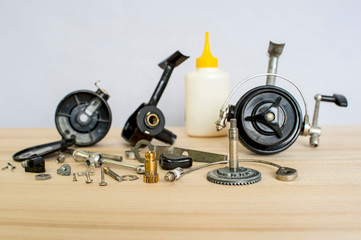 A fishing spinning reel as a whole and a second similar completely disassembled. Concept: parts of a whole. Preparation for the fishing season: prevention and application of lubrication.