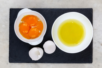Ingredients chicken eggs. Yolks and squirrels in different bowls on a black background.