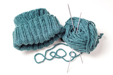 Knitted hat, knitting needles and skein on a white background