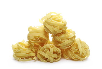 Raw tagliatelle pasta noodles isolated on white background