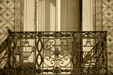 Rusty forging balcony and ceramic tiles (azulejos) wall. Architectural detail of typical old building in the centre of Lisbon (Portugal).Sepia photo..