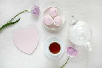 Valentine's Day. Breakfast in a romantic style. Tea, pink marshmallow, pink heart-shaped plate, pink tulip on a light background