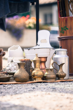 Antique teapots, creamer and other utensils at a flea market. Old metal tableware at a garage sale.
