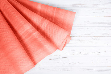 Coral color yoga mat on white wooden background with copy space.
