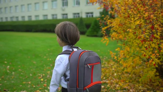 little boy schoolboy student with backpack going to school outdoors. First-grade student, primary school, first grader, first class 1 september school boy child schoolchild day of knowledge Back view