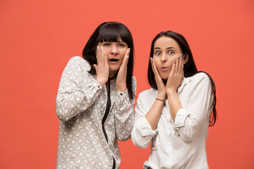 A portrait of a surprised mother and daughter at studio on living coral background. Trendy colors....