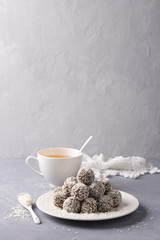 Homemade raw date candies with coconut chips on a gray background, free space. delicious healthy dessert