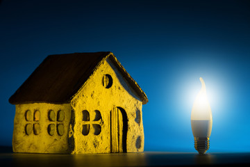 Led lamp stand near the layout of the house on a blue background