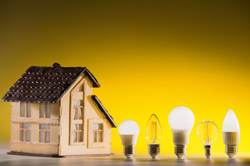 Led lamps stand near the layout of the house on a yellow background