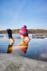 Fit woman performs ice swim in the ice hole. Holding hands above the water protects from fast...