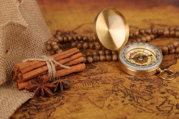 Vintage compass and cinnamon spices on a old world map - trade and explorer concept