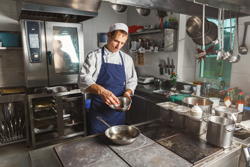 Chef cooking meat at restaurant or hotel kitchen
