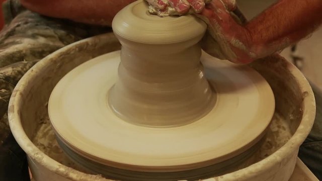 Artist potter in the workshop creating a ceramic vase. Hands detail closeup. Twisted potter's wheel. Small artistic craftsmen business concept. 