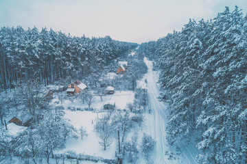 View from above of village lokated in pine forest in snowy winter
