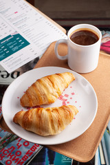 Two delicious croissants with a cup of coffee on the coffee table