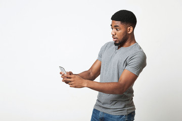 Disappointed african-american man using smartphone on white