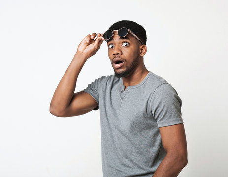 Surprised black man taking off his glasses