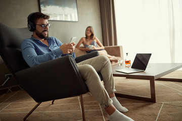 man uses a phone with headphones to listen to music and relax at home.