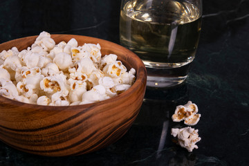 Salt popcorn and whiskey glass on the marble table, selective focus