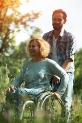 Happy woman in wheelchair with her husband. Outdoors
