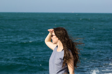 Fototapeta na wymiar girl in black glasses by the sea looking into the distance