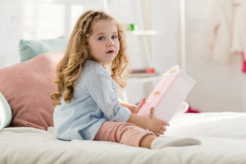 adorable kid playing on bed in children room