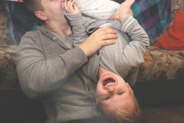 Dad and son play, indulge. The father turned his son upside down, the child laughs