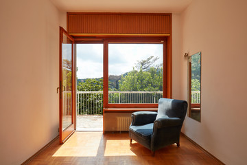 Sunny room interior with oen window and blue velvet armchair in country house