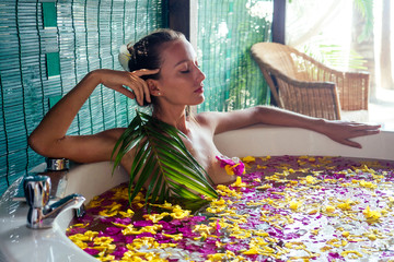 naked brunette young woman relaxing in bath with petals in tropics. Time for yourself.romantic 14 february valentine day in the spa salon eco hotel,summer vacation in a tropical paradise on the beach