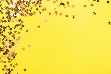 Golden shining stars confetti on yellow