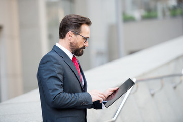 Fototapeta premium Profile of concentrated mature manager using a tablet in the street