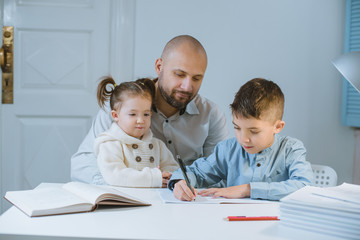 Father with his children have fun sitting at a table.