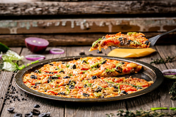 Top view of pizza with bacon and cheese with food ingredients on a wooden board. Raw vegetables on a wooden background. space for text