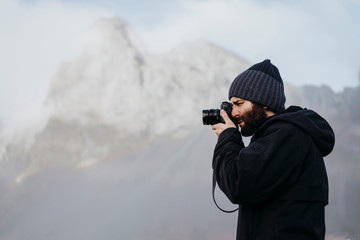 Anonymous tourist with camera against mountain in Iceland