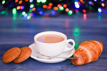 Coffee time christmas eve. Fresh brewed coffee in white cup or mug on defocused garland lights background. Coffee drink winter holiday new year. Enjoying coffee on christmas morning
