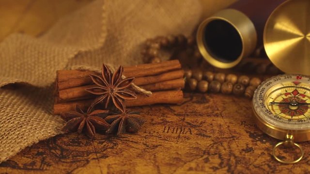Vintage compass with spyglass telescope and cinnamon spices on an old world map - trade and explorer concept