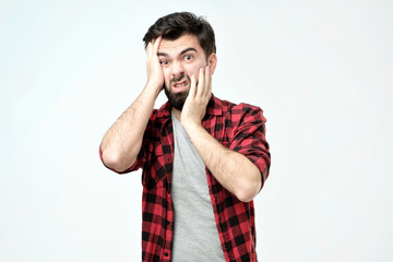 Fright concept. Portrait of the scared man. Hispanic man in fear holding his hands on head feeling...