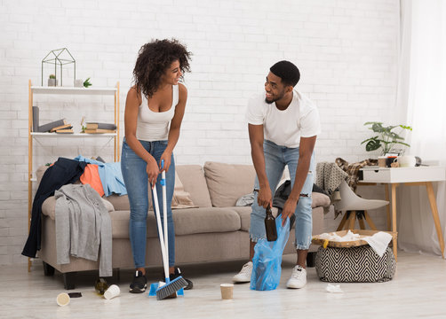 Man and woman cleaning messy room after party