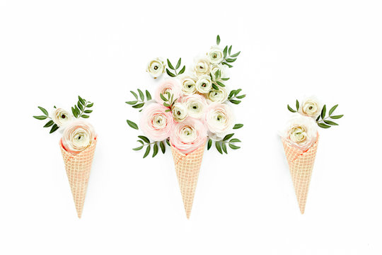 Waffle cone with ranunculus flower bouquet on white background. Flat lay, top view floral background.
