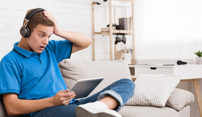 Shocked teen guy reading news on tablet