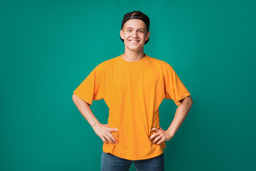 Handsome teenager with hands on hips over turquoise background