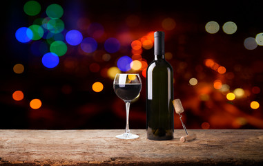red wine glass near bottle with light bokeh in background