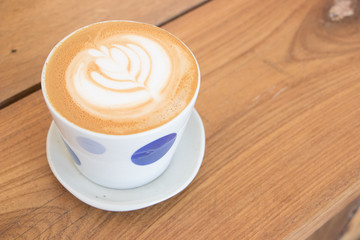 coffee cup latte art on wooden table.hot drink coffee with milk froth for breakfast.heart shape art foam texture top view.