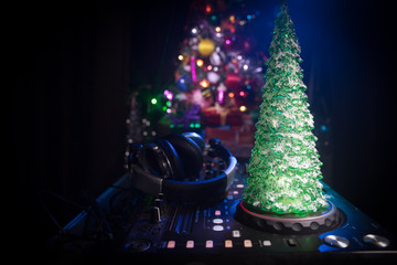 Dj mixer with headphones on dark nightclub background with Christmas tree New Year Eve. Close up...
