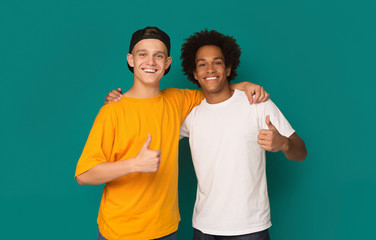 Diverse teens showing thumbs up over blue background